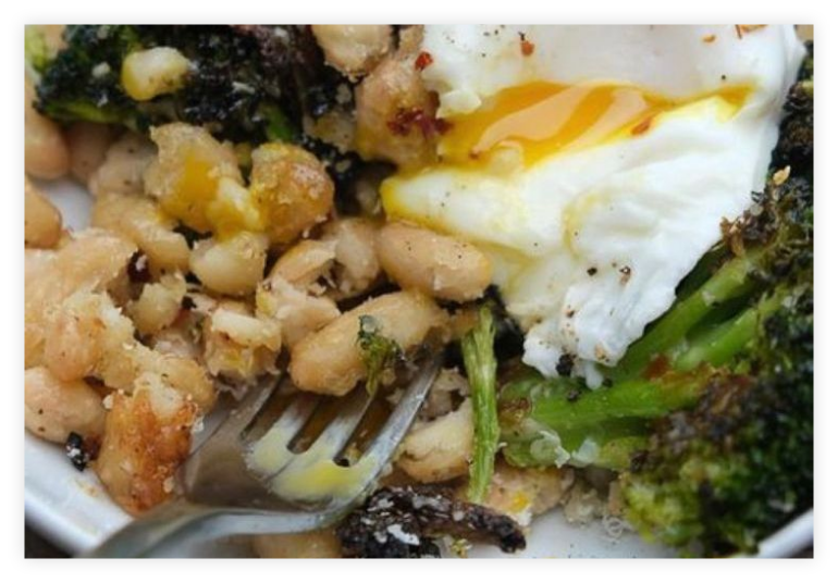 Close up detail of breakfast food, egg, greens, beans